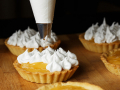 A process of decorating lemon tartlets with meringue icing